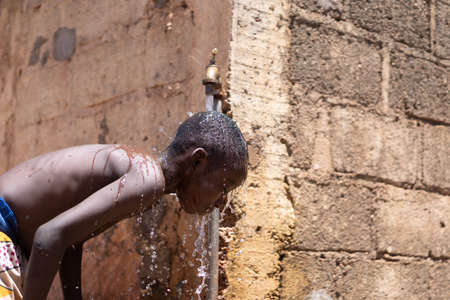 Hygiene symbol, African black boy washing under tapの写真素材