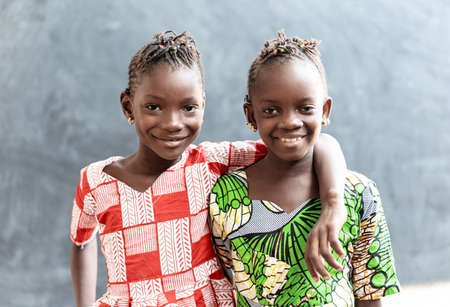 Two African Sisters Laughing and Smiling Outdoors with Toothy Smiles before Schoolの写真素材