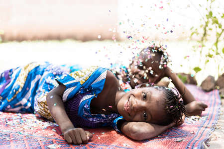 Two Gorgeous African Children Girls Having Fun with Confetti Outdoorsの写真素材