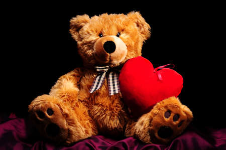 A teddybear with big red heart on black backgroundの写真素材