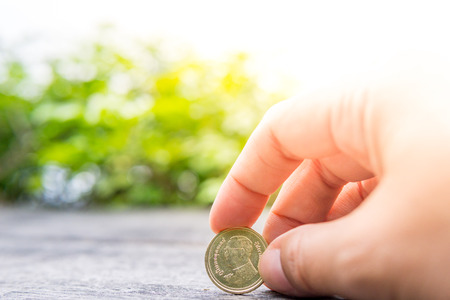 Close up hand putting coins in tableの写真素材