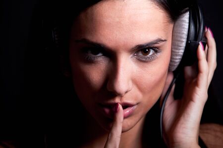 Attractive girl showing shh and listening music on her headphones. Close-up taken with 5d mark II の写真素材