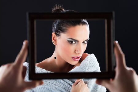 Gorgeous woman in bathrobe looking at camera through the picture frame. の写真素材