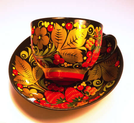 Porcelain cup and saucer from a tea set covered in Russian style in Khokhloma.