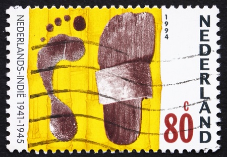 NETHERLANDS - CIRCA 1994: a stamp printed in the Netherlands shows Footprint and Sandal, War in Dutch East Indies, 1941-45, circa 1994の写真素材