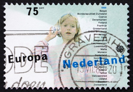 NETHERLANDS - CIRCA 1989: a stamp printed in the Netherlands shows Girl and String Telephone, Childrens Games, circa 1989のeditorial素材