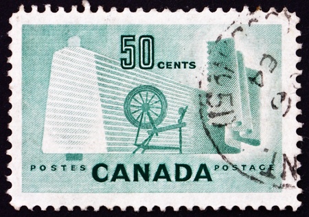 CANADA - CIRCA 1953: a stamp printed in the Canada shows Bobbin, Cloth and Spinning Wheel, Production of Textile, circa 1953のeditorial素材