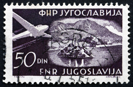 YUGOSLAVIA - CIRCA 1951: a stamp printed in the Yugoslavia shows Plane over Bled, Lake in Slovenia, circa 1951のeditorial素材
