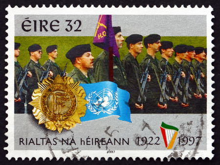 IRELAND - CIRCA 1997: A stamp printed in Ireland shows Irish Defense Forces, Badges and UN Flag, circa 1997のeditorial素材