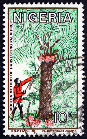 NIGERIA - CIRCA 1986: a stamp printed in Nigeria shows Modern method of harvesting palm fruit, circa 1986のeditorial素材