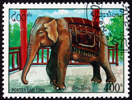 LAOS - CIRCA 1994: a stamp printed in Laos shows elephant beside railing, circa 1994のeditorial素材