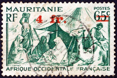 MAURITANIA - CIRCA 1938: a stamp printed in Mauritania shows family before tent, circa 1938の写真素材