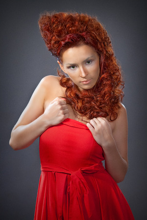 the girl with red hair in a red dress closeupの写真素材