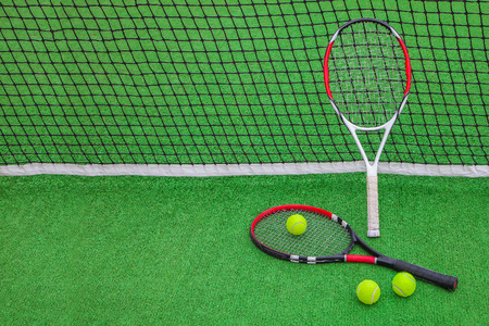 tennis racket with balls on green backgroundの写真素材