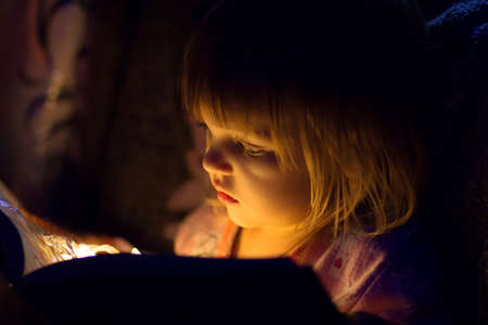 The girl reads the magic book, from the book light on the person, a close up shinesの写真素材