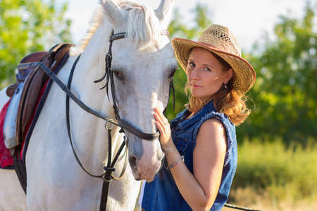 The girl in a hat irons a white horseの写真素材
