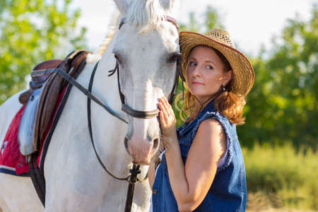 The girl in a hat irons a horse on a muzzleの写真素材