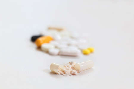 Contents of the opened capsule against the background of tablets, medicine, powderの写真素材