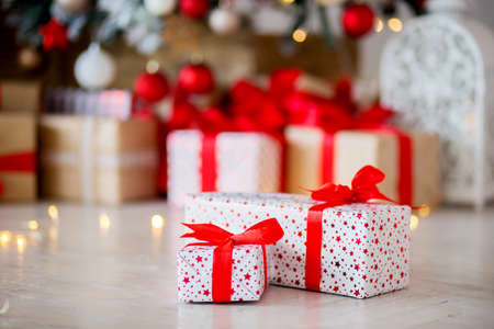 The gift in red packing lies on a floor against the background of other gifts, bokehの写真素材