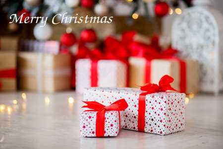 The gift in red packing lies on a floor against the background of other gifts. Inscription of the Merry Christmasの写真素材