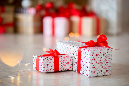 The gift in red packing lies on a floor against the background of other gifts, bokehの写真素材