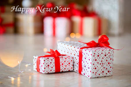 The gift in red packing lies on a floor against the background of other gifts. Inscription Happy New Yearの写真素材