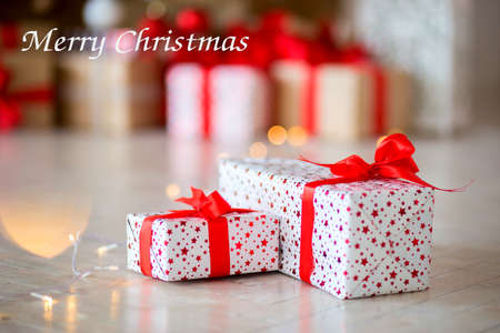 The gift in red packing lies on a floor against the background of other gifts. Inscription of the Merry Christmasの写真素材
