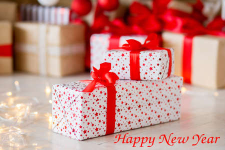 The gift in red packing lies on a floor against the background of other gifts. Inscription Happy New Yearの写真素材
