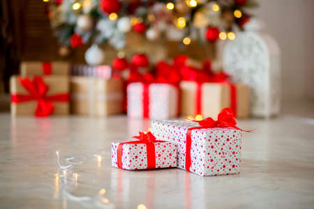 The gift in red packing lies on a floor against the background of other gifts, bokehの写真素材