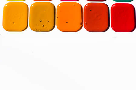 Multi-colored bright Watercolor paints of warm shades close up. A frame from paints on a white background.の写真素材