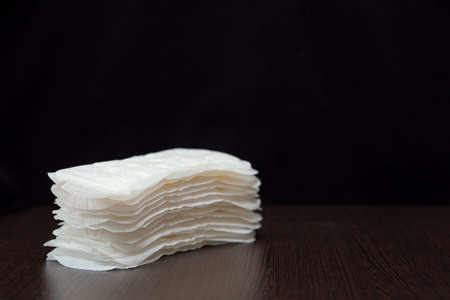 Women's white sanitary pads for every day are stacked on a black backgroundの写真素材