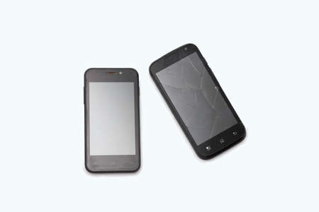 Two black phones lie on a white background. The broken smartphone. Cracks on the screen.の写真素材