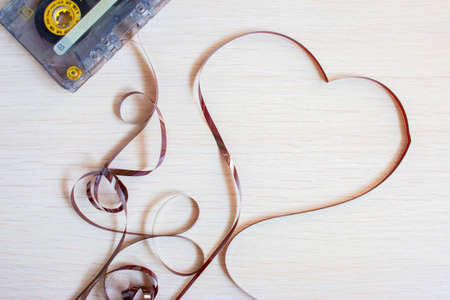 Heart from an old recorder cassette tape on a wooden background.の写真素材