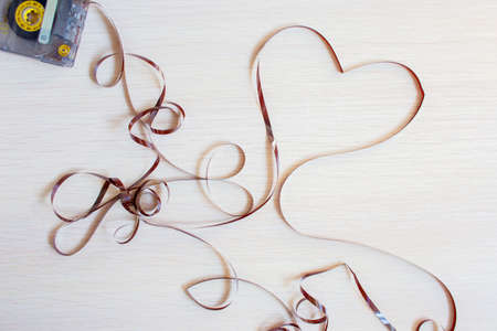 Heart from an old recorder cassette tape on a wooden background.の写真素材