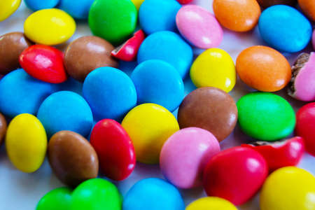 Many multi-colored small round candy pills are scattered on the table close-upの写真素材
