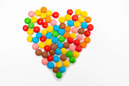 Multi-colored round candy tablets are collected in the form of a heart on a white background for Valentine's Day.の写真素材