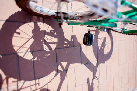The shadow of a children's bike and spoked wheels on paving stones in the park. Healthy lifestyleの写真素材
