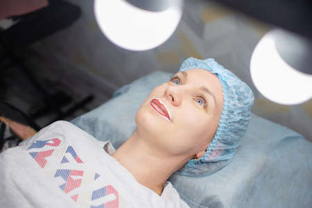 A woman lies on a table in the office of a permanent makeup artist, lips are anesthetizedの写真素材