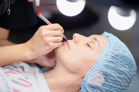 Preparation for permanent lip makeup. Lip contour drawing for tattoo