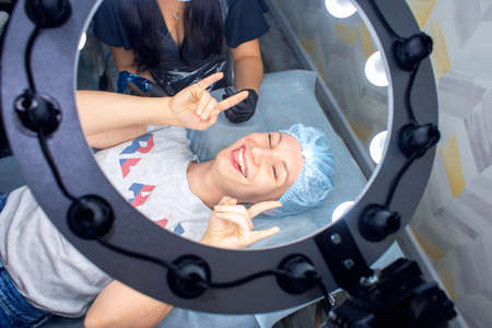Happy woman in beauty salon makes permanent lip makeup and shows how cool it isの写真素材