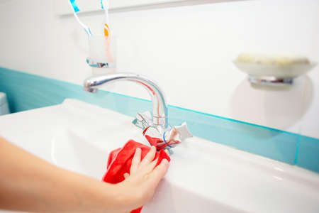 Washing the sink and faucet in the bathroom. Disinfection at home. Spring-cleaning. Cleaning the sink with a ragの写真素材