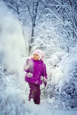 A little girl looks at the fresh snow with enthusiasm. Walk in the winter forestの写真素材