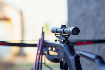 The optical sight of a modern crossbow. A crossbow with arrows for hunting lies on the table