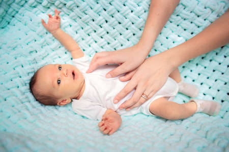 Mom's hands carefully stroke the baby in the crib