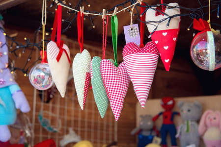 Sewn soft fabric hearts hang on a counter in a fairground tent. Valentine's Day souvenirsの写真素材