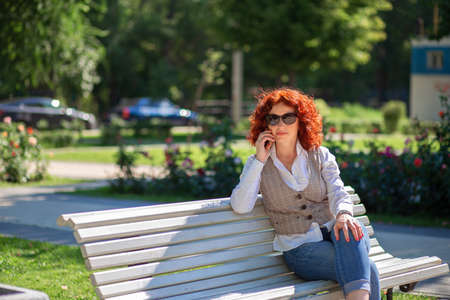 The use of modern technologies in everyday life. Nowhere without a phone. Summer walk and talking on the phoneの写真素材