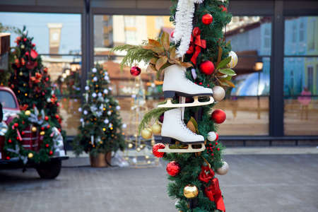 A pair of figure skates hang on a festive Christmas pole in a city park. Original New Year decoration of the cityの写真素材