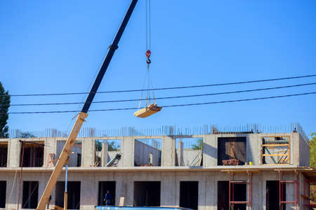 Construction of a multi-storey building in the city. The crane lifts the load at the construction...