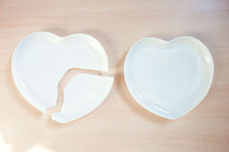 Broken heart-shaped plate. Cracked heart. Shards of broken dishes. Broken heart and whole. Collapseの写真素材