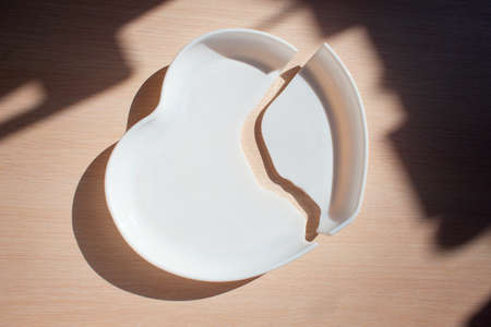 Broken heart-shaped plate. Cracked heart. Shards of broken dishes. The plate fell to the floor and shatteredの写真素材